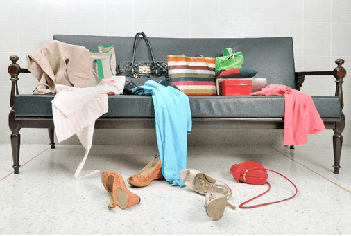 Clothes, shoes, and accessories thrown all over floor and a coach