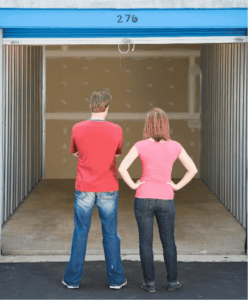 Couple is standing in front of an empty storage unit deciding how to organize it