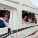 A family leaning out the windows of a RV