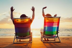 Two adults in colorful beach chairs raising arms in excitement