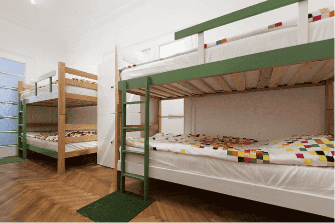 A college dorm room with two sets of bunk beds against the wall.