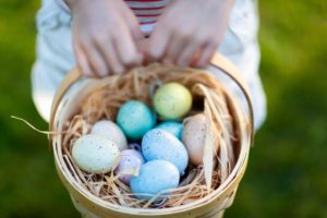 child holding basket full of colorful eggs