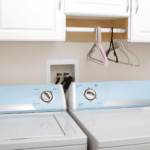 A washer-dryer combo under white cabinetry in a laundry room.