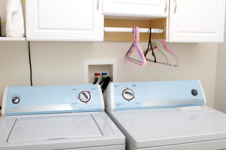 A washer-dryer combo under white cabinetry in a laundry room.