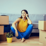 A woman sitting on the floor with moving boxes all around her