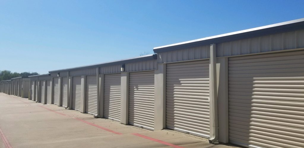 A row of outdoor storage units with large white doors in a clean area