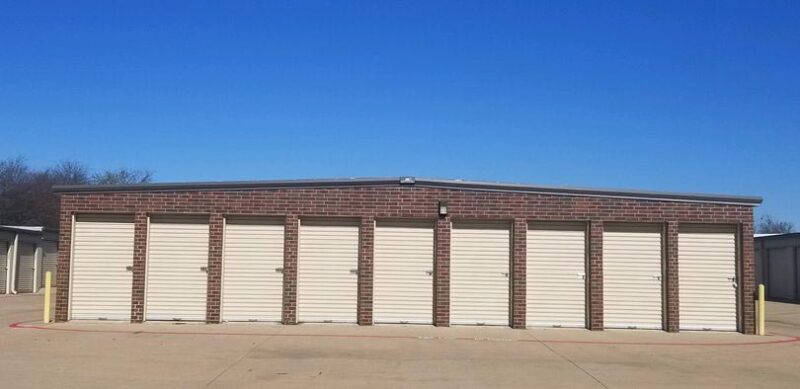 A row of small, outdoor storage units with white doors
