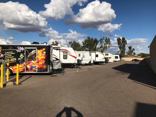 An outdoor parking lot with RVs and trailers parked next to each other