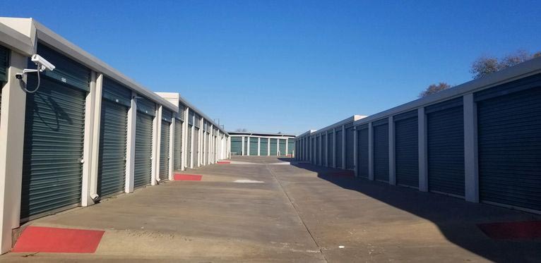 A row of large outdoor storage units with green doors in a clean area