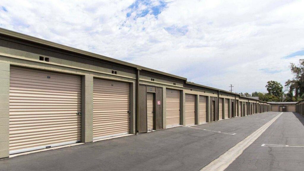 A long row of large outdoor storage units with yellow doors in a clean area