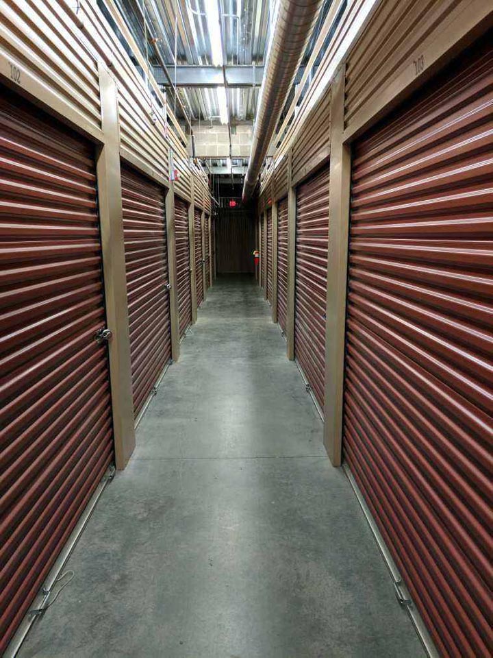 Clean hallway of large indoor storage units with red doors