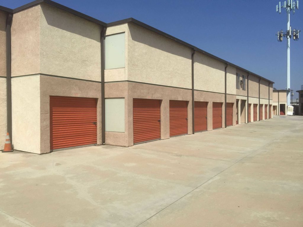 A row of large outdoor storage units with red doors