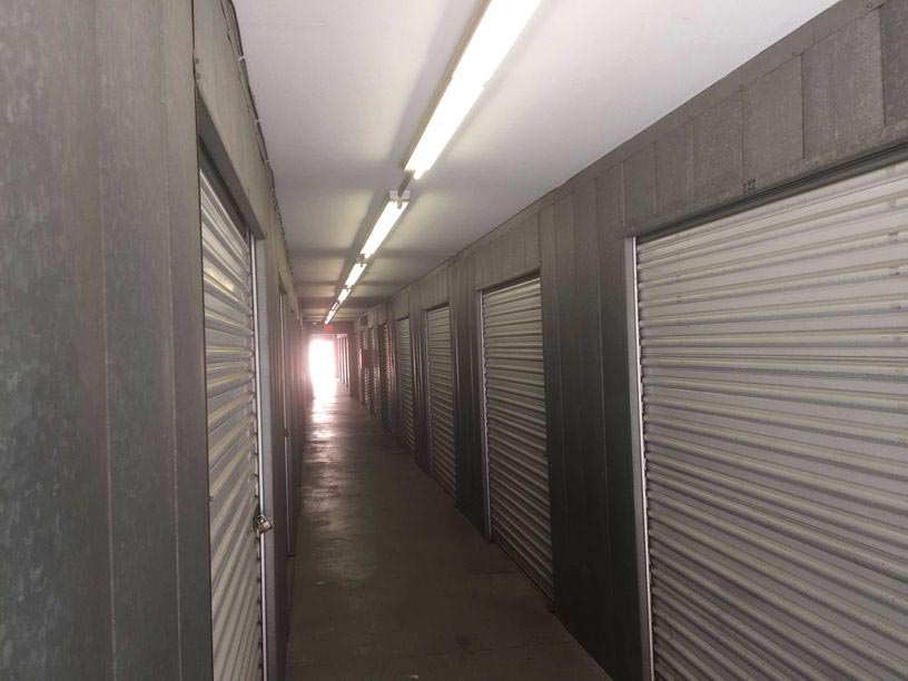 Indoor hallway of storage units with grey doors and secure locks