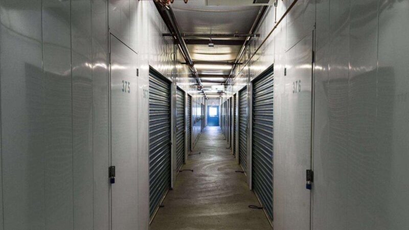 A hallway of large indoor storage units with blue doors