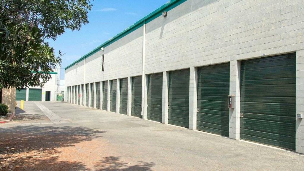 A row of large outdoor storage units with green doors in a clean area