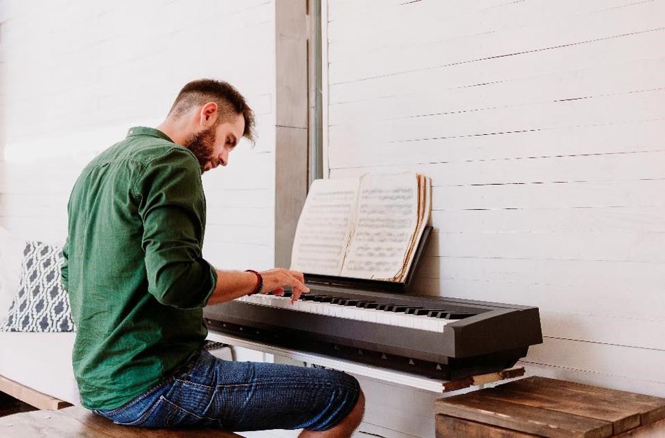 man sitting at at keyboard playing sheet music