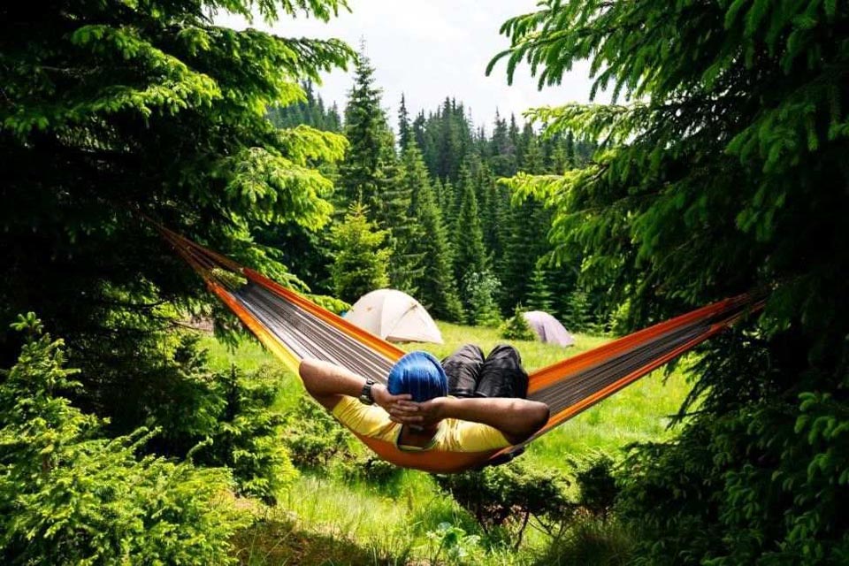 A person laying on a hammock overlooking scenery