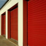 Row of outdoor storage units with large, red doors in a clean area