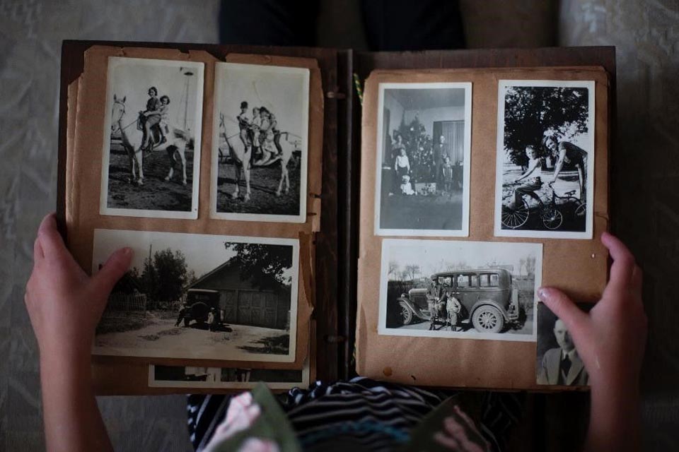 A first-person view of a child's perspective, holding and looking at a black-and-white photo album.