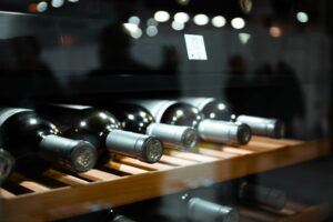 Several glass bottles of wine lay on a shelf inside of a climate controlled refrigerator