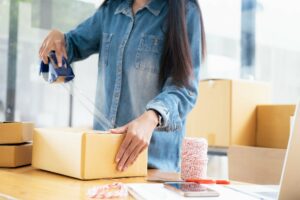 A small business owner tapes up a box as they prep it for storage