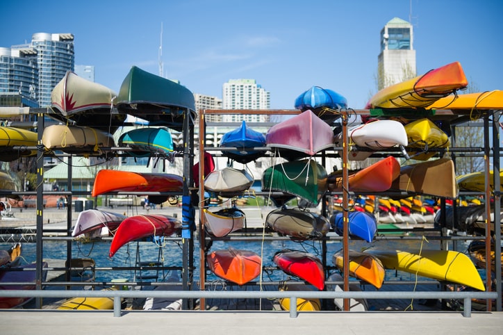 Colorful kayaks in many different sizes rest on shelves on a pier.