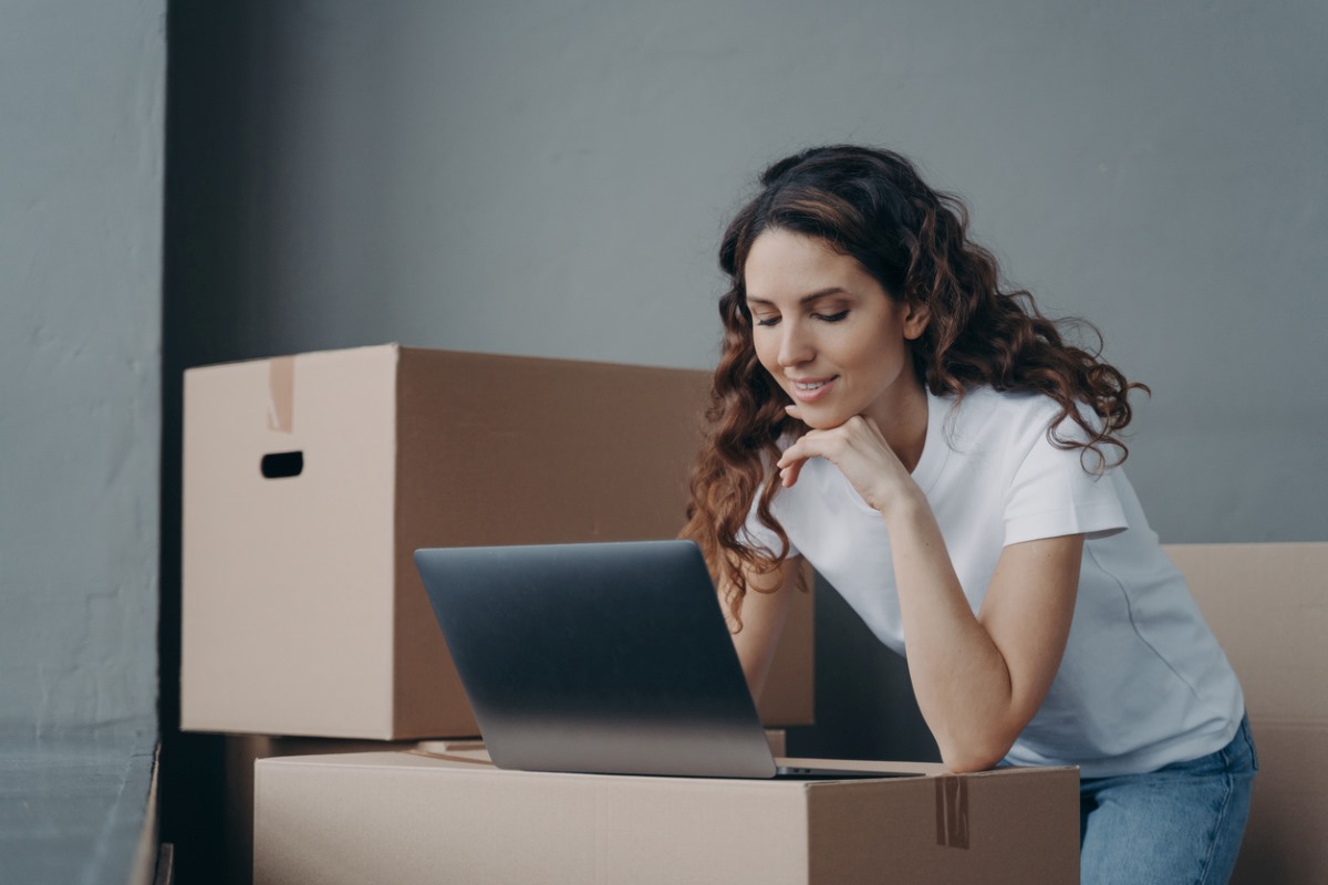 Businesswoman works on a laptop with cardboard storage boxes all around.